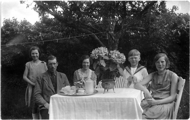 Familjen Karlsson vid kaffebord i trädgården